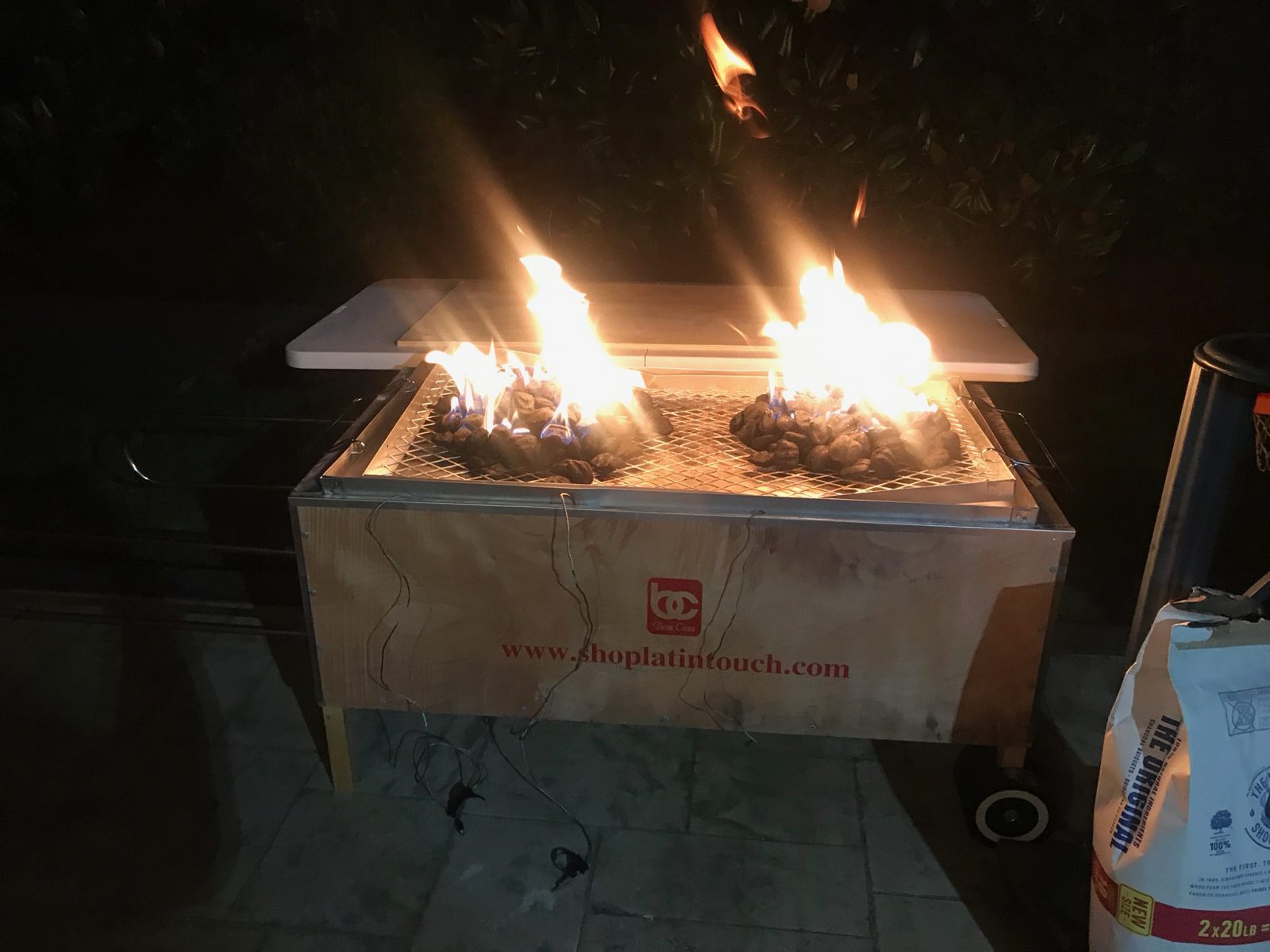 Flames rising from the charcoal tray above the roasting box at night