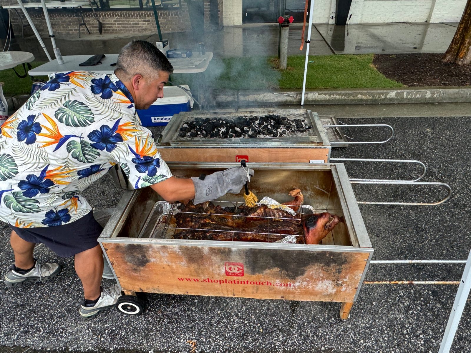 Dan brushing the hog with a basting mop in the open roasting box