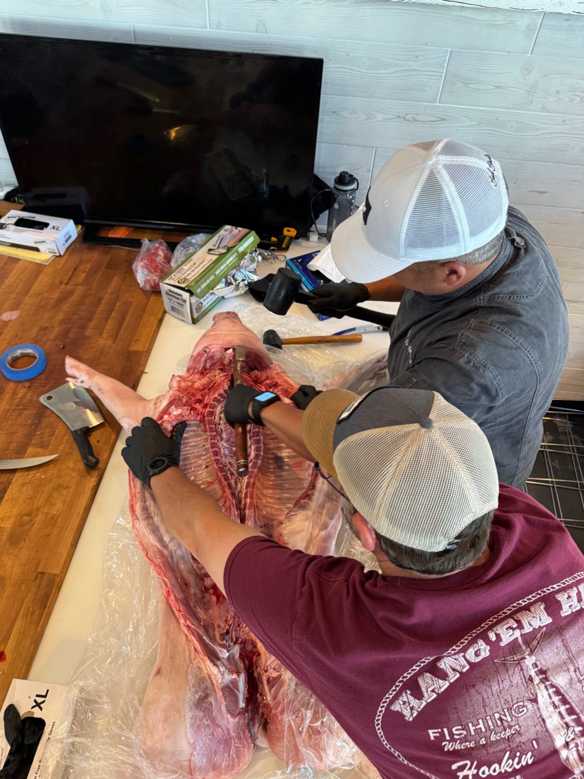 Overhead view of two people preparing the opened whole hog