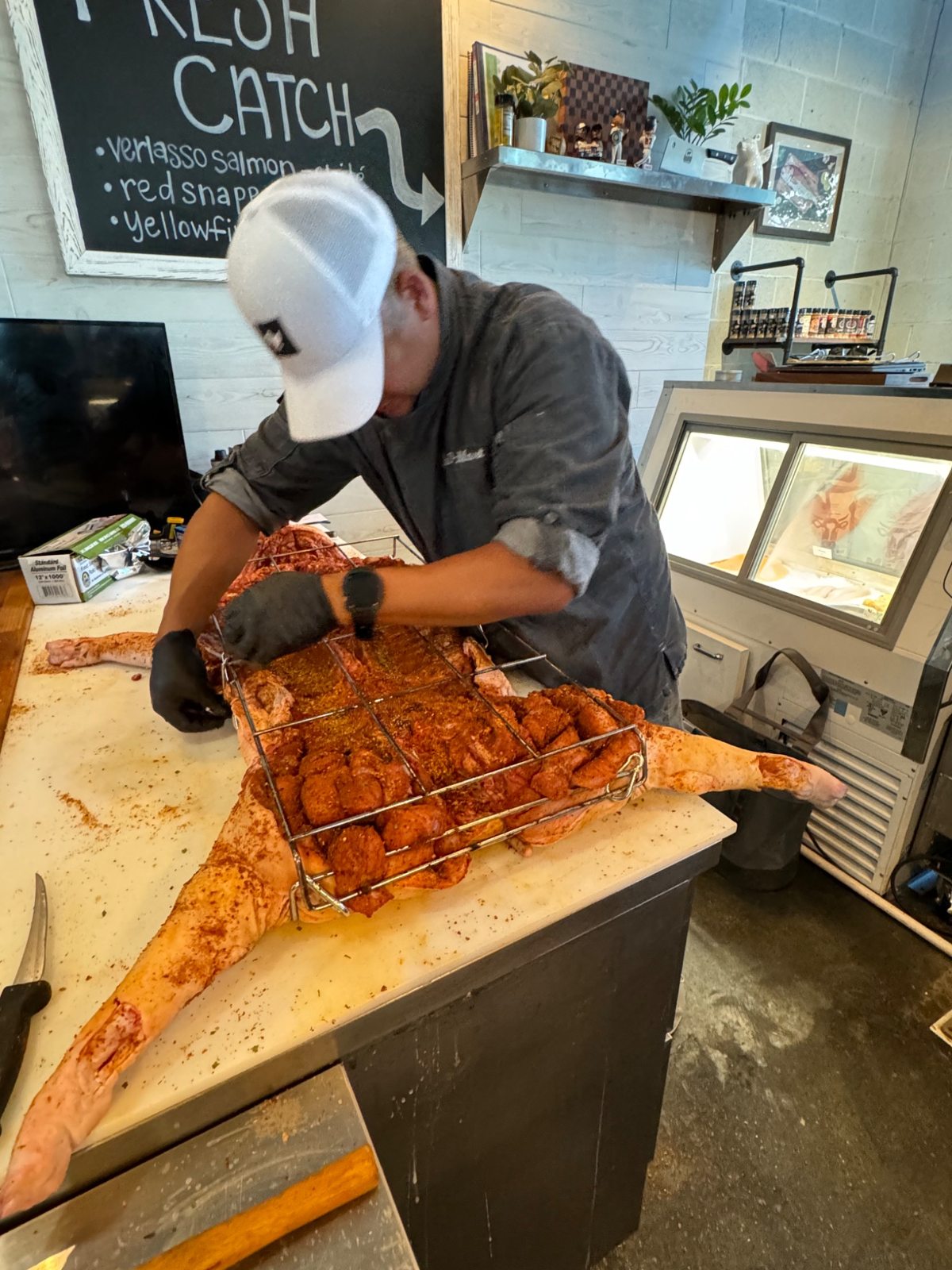Dan fastening a metal roasting rack around a seasoned whole hog