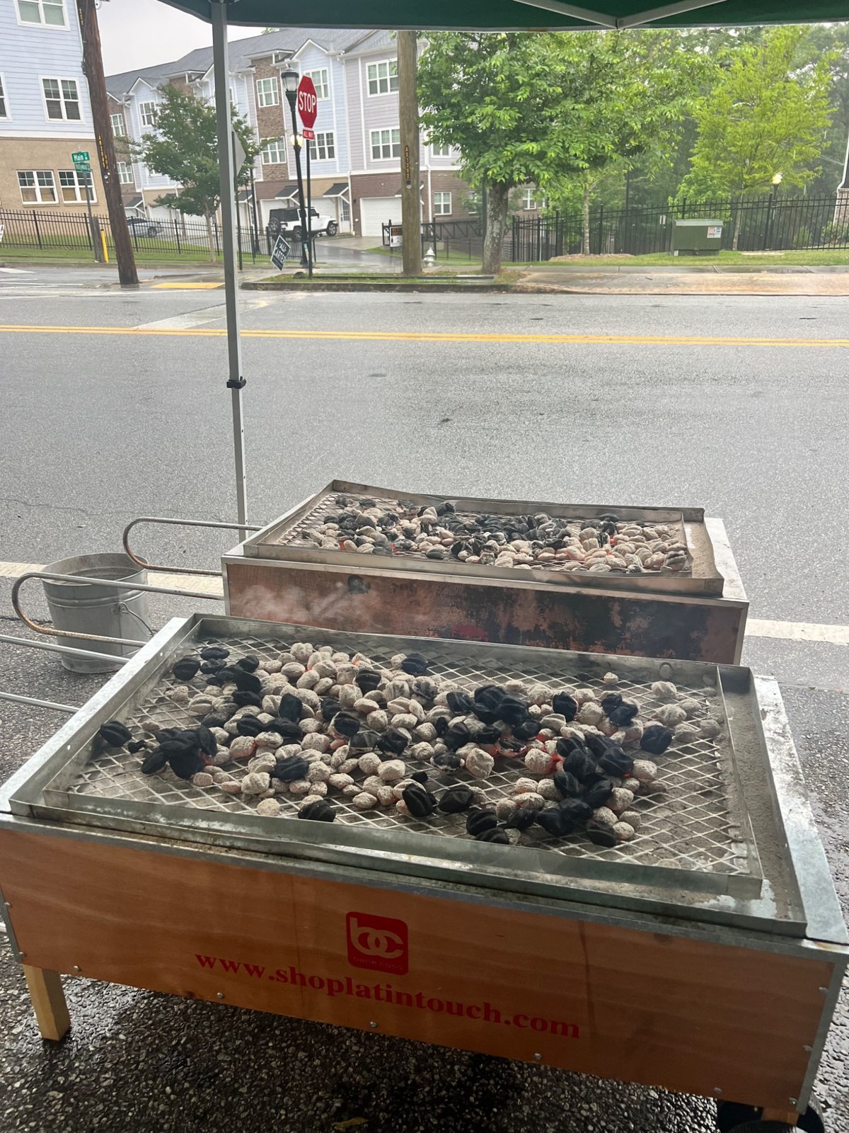 Two roasting boxes cooking side by side under a canopy with charcoal on top