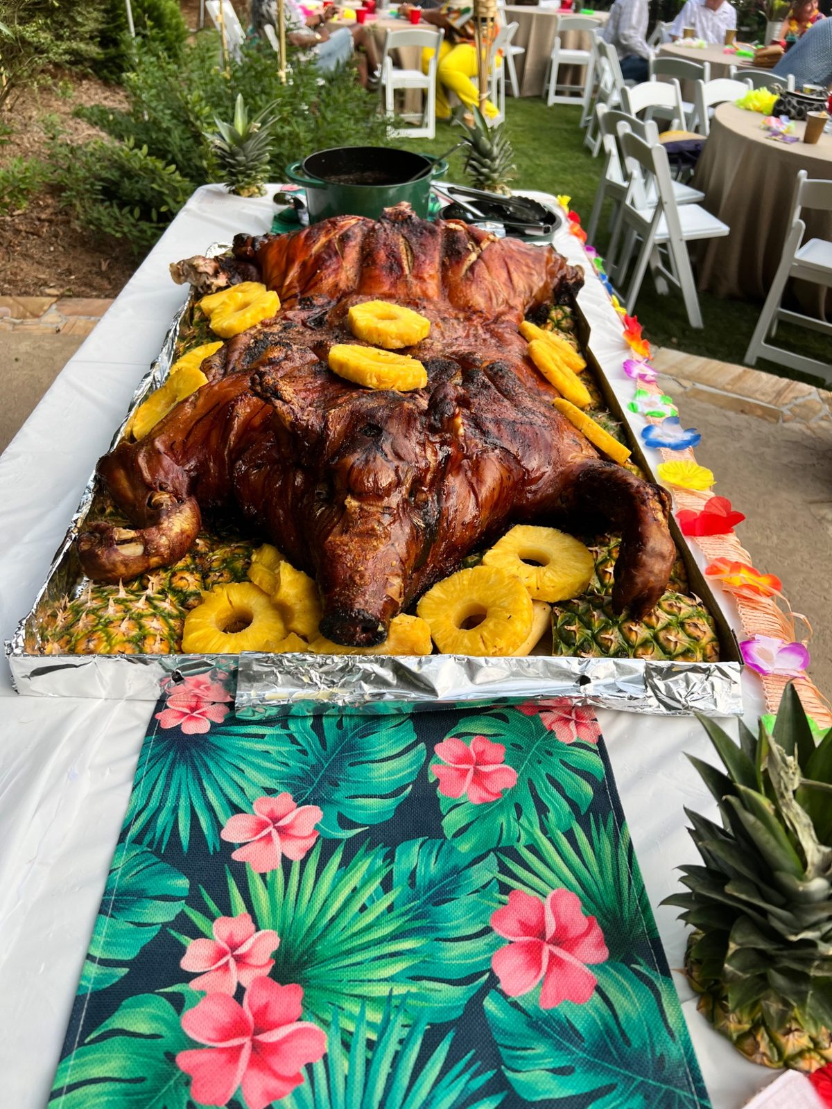Whole roasted hog presented with pineapple at a luau themed divorce party
